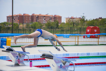 Un nadador se tira a la piscina, ya sin la grada móvil que hubo durante los Juegos y que permite ver, en el fondo, Campclar.