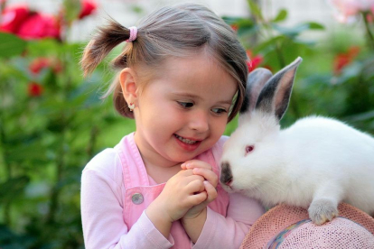 Nena amb un conill com a animal de companyia.