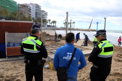Agentes de la Guardia Urbana de Salou, hablando con el propietario de un chiringuito de los daños que ha sufrido la terraza a causa del temporal, en un extremo de la playa de Levante.