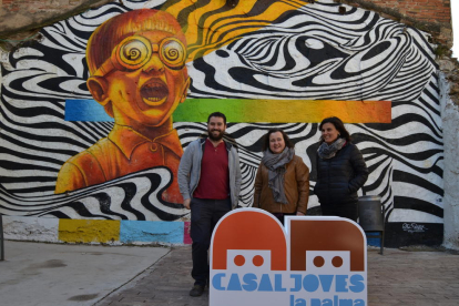 La regidora Montserrat Flores (centre) i dues persones responsables del Casal de Joves davant un mural de «Llambordes 2017»
