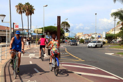 Turistes en bicicletes al Passeig Marítim de Cambrils on es va produir l'atemptat terrorista ara fa un any.