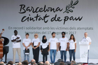 Plano general del escenario de plaza Catalunya donde hay las ocho personas encargadas de leer el manifiesto en recuerdo de las víctimas del 17-A.