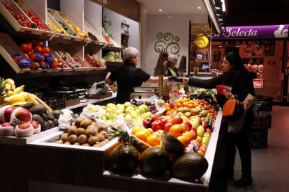 Pla obert d'una clienta pagant la compra en una parada de fruites i verdures del Mercat Central de Tarragona. Imatge del 15 de març del 2018