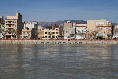 Lletres de la pintada 'El riu es vida' a Tortosa parcialment cobertes per l'aigua.
