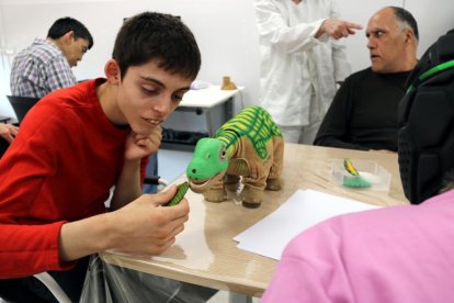 Un joven con trastorno mental interactuando con un peluche de dinosaurio, uno de los robots que ha adquirido el centro Villablanca, del grupo Pere Mata de Reus, para estimular a sus usuarios.