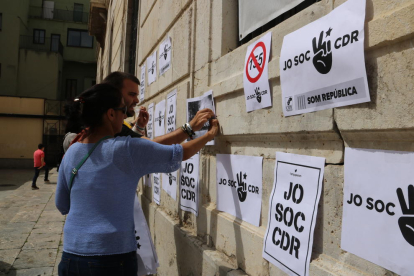 Pla mig d'una persona enganxant un cartell a la façana de l'Ajuntament de Tarragona pel CDR.