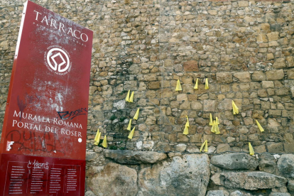 Pla mig de la Muralla de Tarragona amb llaços grocs i un cartell informatiu en primer terme.