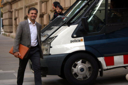 Plano medio de Oriol Pujol llegando a la Audiencia de Barcelona, pasando por delante de un furgón de los Mossos.