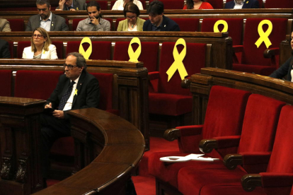Un llaç groc a la bancada del Govern tombat, amb el president de la Generalitat, Quim Torra, de fons, i amb altres llaços de fons.