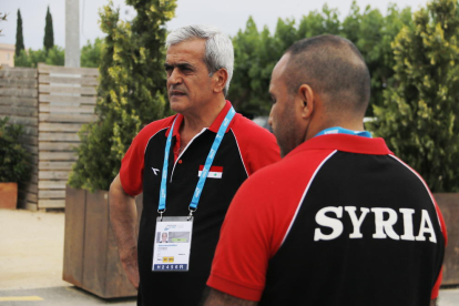 El cap de missió de la delegació de Síria als Jocs Mediterranis, Mohammad Harba. En primer pla, un altre membre de la delegació siriana amb la samarreta amb el nom del país.