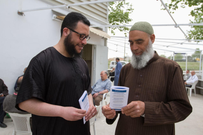El portavoz de la mezquita, a la izquierda, muestra la información de los folletones que repartirá el centro.