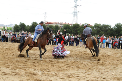 Dues noies vestides de sevillanes ballen rodejades de dos cavalls molt esvelts.