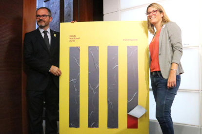 La portaveu del Govern, Elsa Artadi, i el vicepresident primer del Parlament, Josep Costa, amb el cartell de la Diada de l'11-S.