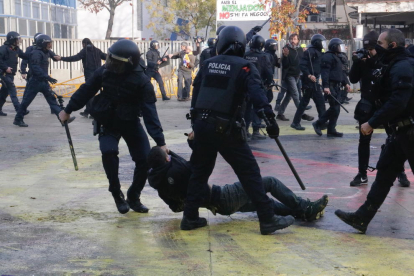 Dos agents dels Mossos, arrossegant un manifestant antifeixista a la plaça U d'Octubre de Girona.