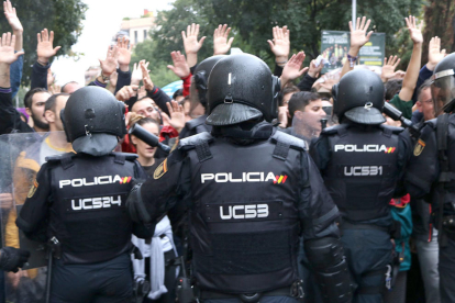 agents de la policia espanyola d'esquenes intentant impedir el pas de ciutadans que feien cua per votar a l'Escola Ramon Llull, l'1 d'octubre de 2017