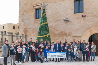 Fotografia de grup de les famílies que han rebut el Xec Nadó el 2018 junt a l'alcalde, Roc Muñoz, i diversos regidors del consistori.