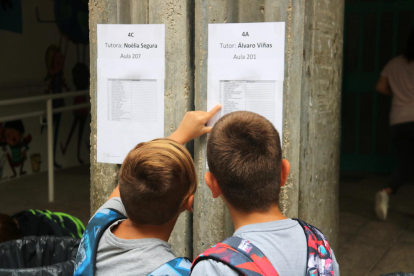 Dos nens observant la llista d'alumnes per aula a l'entrada de l'escola de Ferreries.