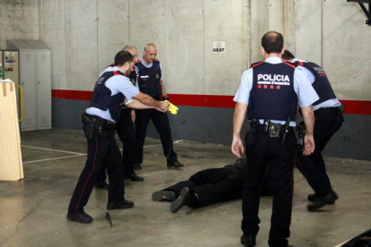 Mossos d'esquadra hacen prácticas con la pistola eléctrica, conocida como Taser; al suelo, un agente, vestido con protecciones, después de que le hayan disparado en la recreación de una situación.