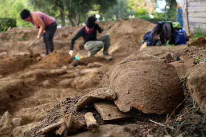 Restes de ceràmica trobades en un gran jaciment iber a Cubelles, amb els arqueòlegs treballant al fons.