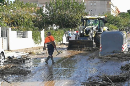 Els operaris i una màquina retirant fang i canyes en un carrer del barri de la Salut, a Salou.