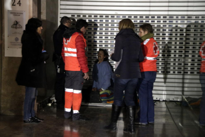 Pla obert de voluntaris de la Creu Roja i de membres de Serveis Socials atenent un sensesostre que dorm a l'entrada d'una botiga del carrer Unió de Tarragona. Imatge de l'11 de gener del 2018