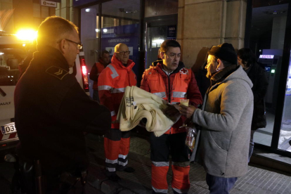Pla americà de voluntaris de la Creu Roja lliurant una manta i un got de caldo a en Francisco Moreno, un sensesostre que passa la nit en un caixer de Tarragona. Imatge de l'11 de gener del 2018
