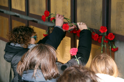 Algunos familiares depositante claveles encarnados bajo las placas que recuerdan a las víctimas de la Guerra Civil al memorial de Camposines.