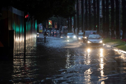 Varios coches circulan esta mañana por la calle Plano de San Francisco de Murcia, inundada tras las intensas lluvias caídas esta madrugada.
