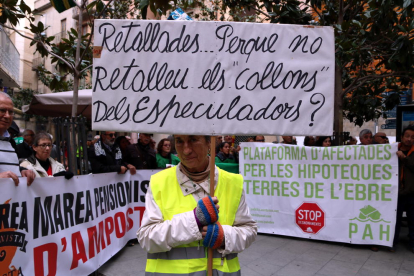Una manifestant amb una pancarta reivindicativa en la mobilització en defensa dels drets socials i per revertir les retallades a Tortosa.