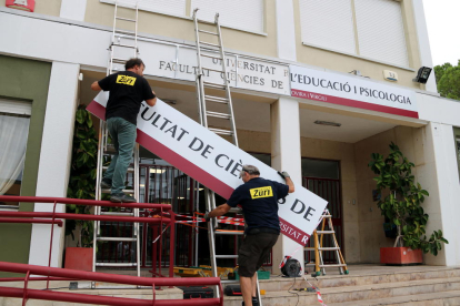 Dos operarios instalando el nuevo letrero de la Facultad de Ciencias de la Educación y Psicología de la URV.