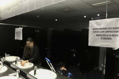 En primer terme, cartell informatiu en el mirall dels lavabos públics de dones del Mercat Central.