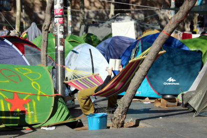 Una persona descansa leyendo a la acampada de Plaça Universitat.