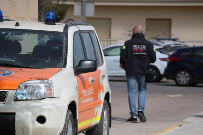 Un vehicle de protecció civil a Deltebre amb un agents dels Mossos sortint de l'Ajuntament amb caixes de documentació.