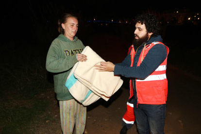 Un voluntario de Cruz Roja entrega una manta a la Catarina, que duerme bajo el río Francolí con su pareja y una amiga.