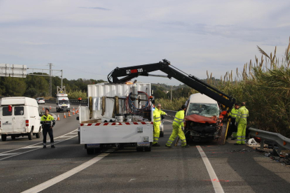 Una grua que treballa per aixecar i emportar-se el cotxe de la víctima mortal de l'accident a l'N-340 a Tarragona.