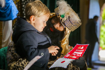 Un nen entrega la seva carta a un dels patges reials que han arribat al municipi
