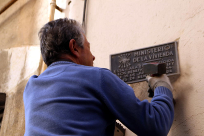Un home que retira una de les set plaques franquistes despenjades, durant la segona acció de les entitats, de les façanes dels edificis dels carrers del centre de Tarragona.