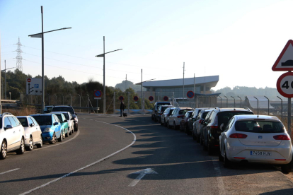 Un passatger que camina amb una maleta després d'aparcar el seu vehicle en el voral de la carretera d'accés a l'estació de l'AVE del Camp de Tarragona.
