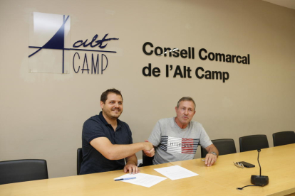 Pla obert d'encaixada de mans entre Joan Maria Sanahuja (JxCat) i Robert Figueras (Alcoverencs pel Canvi), escenificant l'acord de govern al Consell Comarcal de l'Alt Camp per a la legislatura de 2019-2023. Imatge del 15 de juliol del 2019