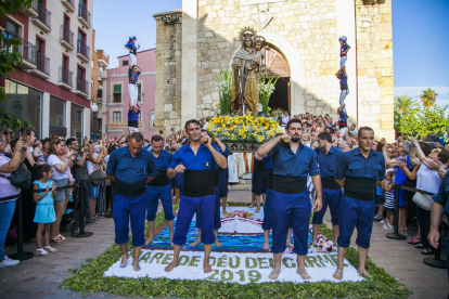 Los portadores de la imagen, parados encima de la alfombra de flores y, en el fondo, dos pilares de los castellers.