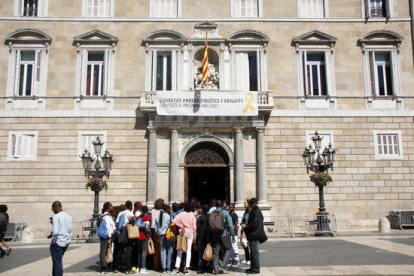 La façana del Palau de la Generalitat amb la pancarta restablerta i un grup de persones mirant la façana aquest 27 de maig.