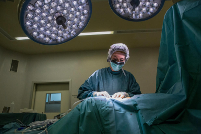 Plano medio de una enfermera haciendo una sutura en una intervención en un quirófano hospitalario.