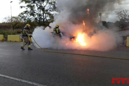 Dos bomberos extingitn el fuego del vehículo.