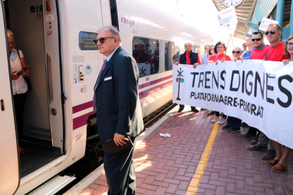 El revisor de l'Euromed a l'estació de l'Aldea davant la pancarta que sostenen activistes de Trens Dignes.
