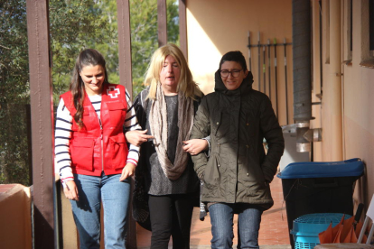Plano americano de la voluntaria Elena Manrique y de dos usuarias paseando por el exterior de la Casa de Acogida de Cruz Roja Tarragona.