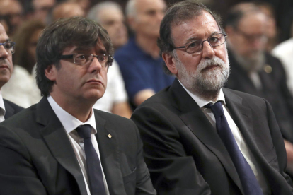 El presidente de la Generalitat, Carles Puigdemont, y el presidente español, Mariano Rajoy, sentados de lado durante la misa a la Sagrada Familia.