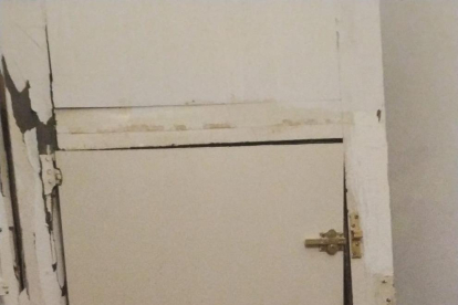 Imagen de una de las puertas del edificio completamente destrozada.