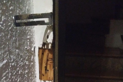 Imagen de la puerta del edificio forzada.