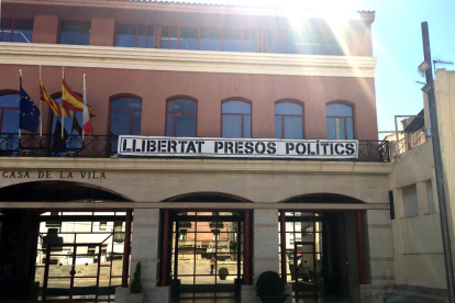 Pla contrapicat de part de la façana de l'Ajuntament d'Alcanar on encara hi ha penjada la pancarta en favor dels presos. Imatge del 27 de març del 2019 (horitzontal)