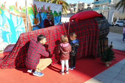 Dos nens fan cagar un tió de grans dimensions a la plaça dels Infants.